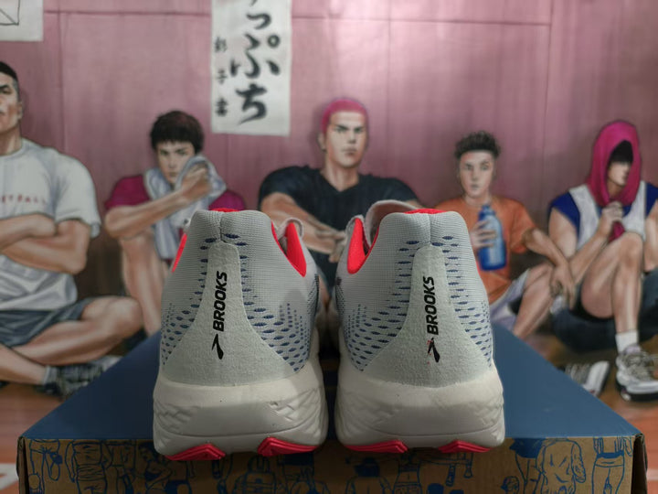 Rear view of white and gray Brooks Hyperion Max shoes with orange-red accents