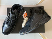 Pair of black high-top basketball shoes displayed with a box and spare light-colored laces.
