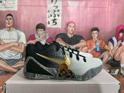 Side view of GiGi basketball sneakers showing black and white panels, gold side branding, black laces, and decorative heart-shaped hangtags.