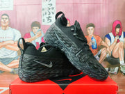 Pair of black and gray Nike sneakers displayed on a red shoebox, showing the textured side panels and Nike Swoosh.
