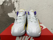 Front view of white Nike sneakers with purple and yellow tongue details and white laces.
