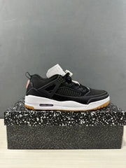 Side view of black and white Jordan Spizike Low sneakers displayed on a patterned shoe box.