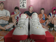 Front view of white Nike basketball sneakers with white laces, red outsole accents, and small yellow tongue details.