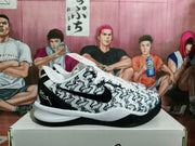 Side view of a white and black Nike basketball sneaker with a patterned upper and black Swoosh.