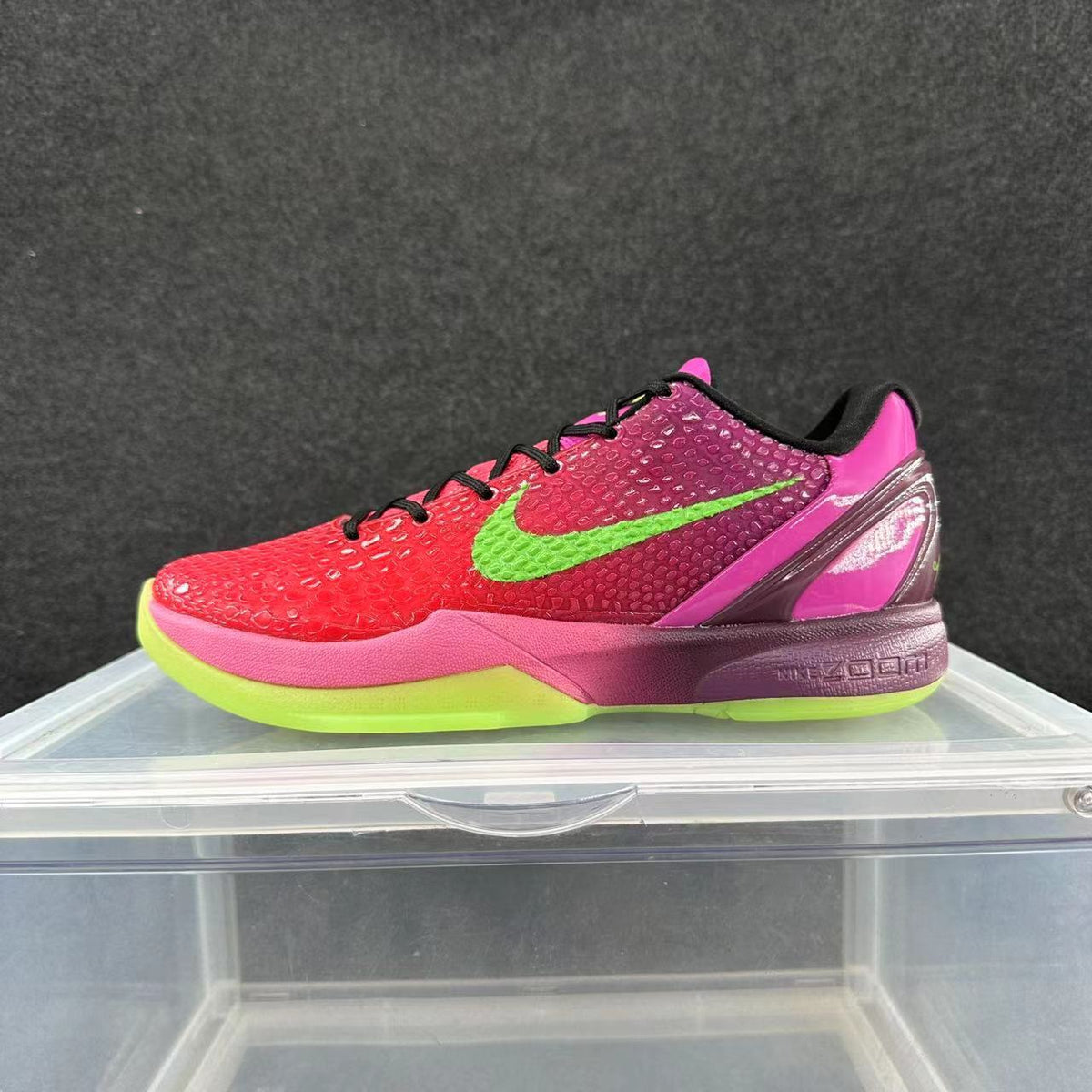 Side view of a red and pink Nike Kobe 6 basketball shoe with a bright green Swoosh and outsole accents, black laces, and a purple-toned midsole.