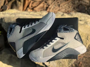Pair of Nike HD2008 sneakers resting on a black box, showing the side panels and contrasting midsoles.