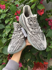 Angled front view of the gray and off-white knit sneaker pair.