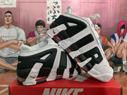 Angled side view of the white and black Nike sneakers highlighting the layered outsole and red-tinted cushioning elements.