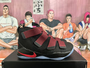 Side profile showing the black basketball sneaker upper, several adjustable straps, red Swoosh-style accent, and light-colored outsole.
