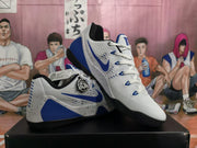 Angled side view of white and blue Nike sneakers showing the blue Swoosh, white laces, black outsole, and speckled midsole.