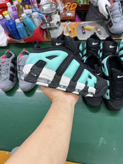 Handheld view of a black and bright green Nike high-top sneaker displayed among other footwear.