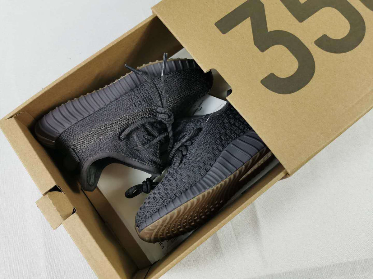 Pair of black and dark gray kids' sneakers shown inside a branded shoebox.
