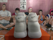 Rear view of white Nike high-top sneakers with Swoosh details near the collars