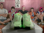 Front view of a pair of light green and white Jordan basketball sneakers with matching laces and black outsole sections.