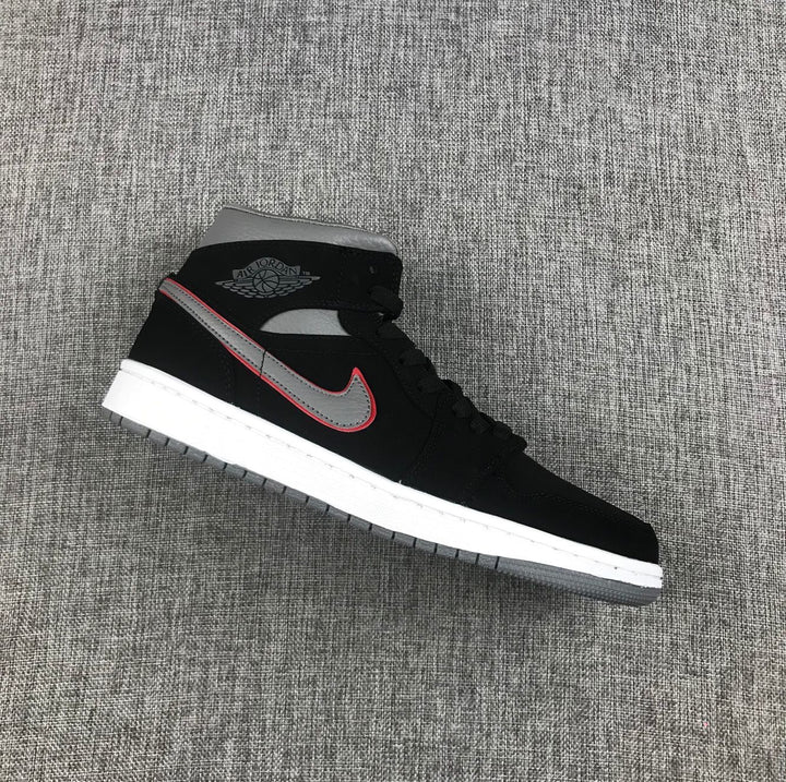 Side view of a black Air Jordan 1 Mid sneaker with a grey and red-edged Swoosh, white midsole and grey outsole.