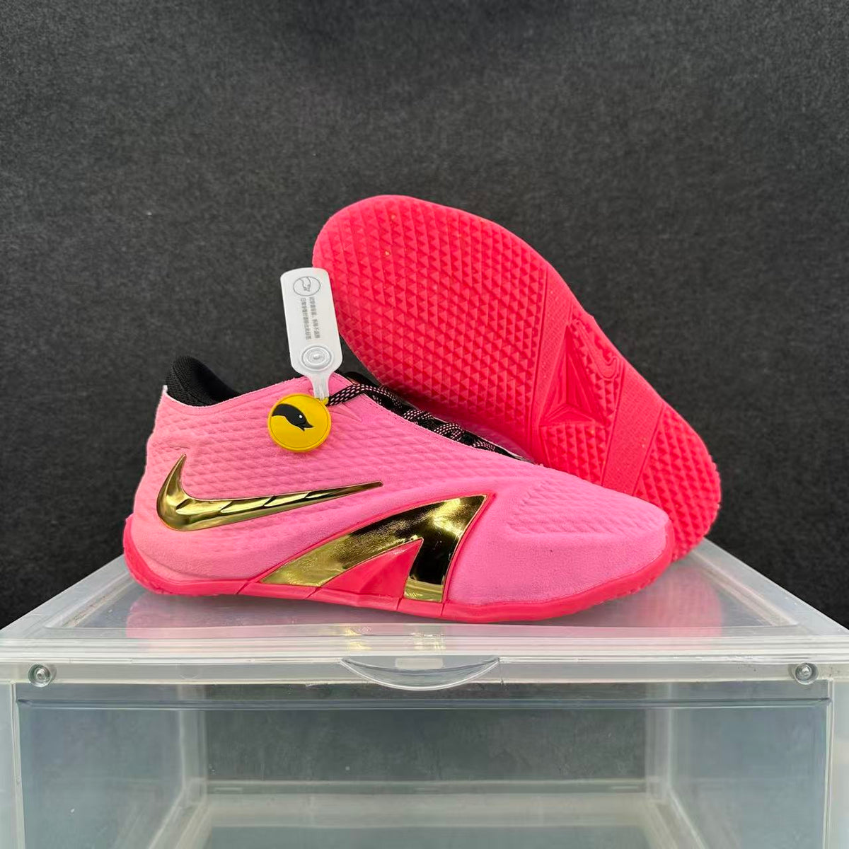 Pink Nike basketball shoe with gold accents beside its patterned outsole