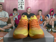 Front view of orange and yellow Nike basketball sneakers displayed on a box.