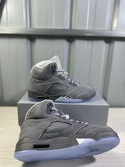 Angled close-up of a grey high-top sneaker highlighting the textured upper, side panel, padded collar, and translucent outsole.