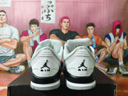 Rear view of the white and grey sneakers showing Jumpman heel logos and black heel accents.