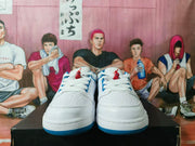 Front view of white low-top sneakers with white laces and blue and red accents
