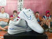 Pair of white low-top basketball shoes with blue side detailing, perforated toes, and green accents.