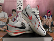 Angled view of the pair highlighting the white upper, red Swoosh, black trim, and lace-up design.