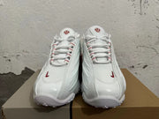 Front view of white lace-up sneakers with red details