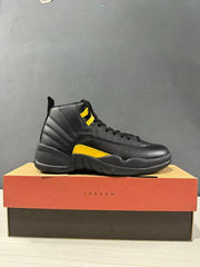 Side profile of a black and yellow Jordan Air Jordan 12 Retro sneaker displayed on a Jordan shoebox.