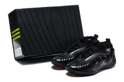 Black sneakers displayed beside a black shoebox, showing red outsole accents and the side detailing.
