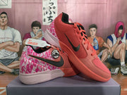 Pair of coral pink Nike basketball sneakers shown from the side, with black Swoosh branding, patterned pink heel panels, and a light-colored midsole.
