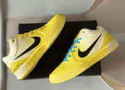 Angled view of the pair displayed on a black surface, with black Swooshes and contrasting blue laces.