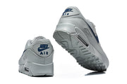 Rear and outsole views of grey and navy Nike Air Max 90 sneakers.