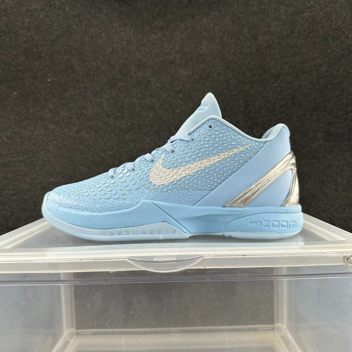 Side view of a light blue-gray Nike Zoom low-top sneaker with a textured upper, pale Swoosh, and metallic-look heel detail.