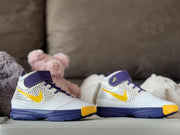 Side view of the paired sneakers highlighting the white uppers, yellow Swooshes, patterned panels, and dark purple soles.