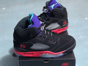 Black and red high-top sneaker pair photographed from the side, with purple tongues and translucent outsole sections.