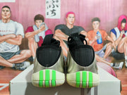 Rear view of silver basketball shoes with black heel panels and bright green sole accents.