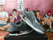 Angled view of grey Jordan low-top sneakers with orange accents