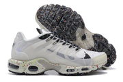 Side view of white sneakers showing translucent panels, patterned laces, and a speckled sole; outsole visible behind