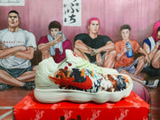 Side view of a cream Nike sneaker with a red Swoosh and multicolor horse artwork across the upper.