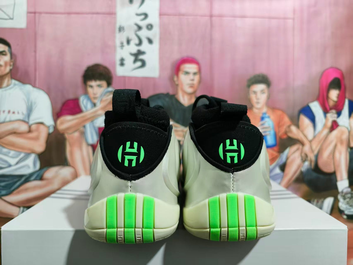 Rear view of cream basketball shoes with black heel tabs and bright green accents.