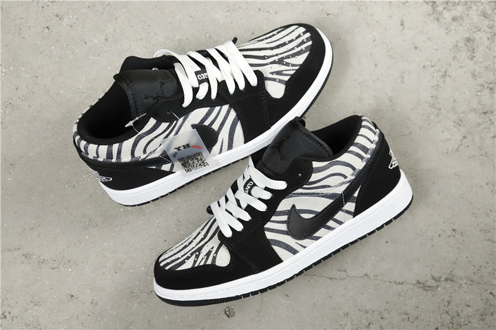 Pair of black, white and gray zebra-patterned Jordan low-top sneakers shown from an angled top view.