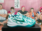 Side profile of a white Nike basketball sneaker with teal-green graffiti lettering, Swoosh and outsole.
