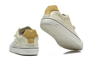 Cream and tan low-top sneakers shown from the heel and outsole.