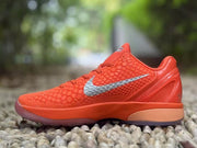 Side profile of the orange sneaker showing the heel structure and contrasting sole section.