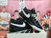 Angled view of the black patterned sneaker pair showing white side branding, white laces, and contrasting black and white soles.