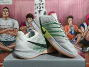 Pair of Nike basketball shoes displayed together, showing the black side Swooshes and teal and lime accents.