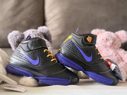 Angled pair view showing the black textured uppers, purple Swoosh-style accents, yellow details and purple outsoles.