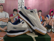 Angled view of paired gray and dark blue Jordan sneakers showing the side panels, blue accents, laces, and gum-colored outsoles.