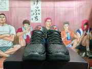 Front view of black textured basketball sneakers with black laces and red tongue logos.