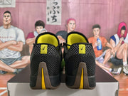 Rear view of black Nike basketball sneakers showing yellow details, gray patterned panels, and brown-and-yellow outsole accents.